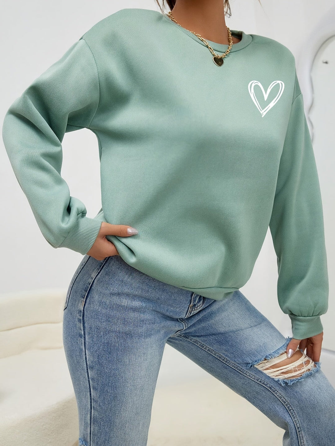 Women's crew neck sweatshirt with long sleeves and heart chest graphic