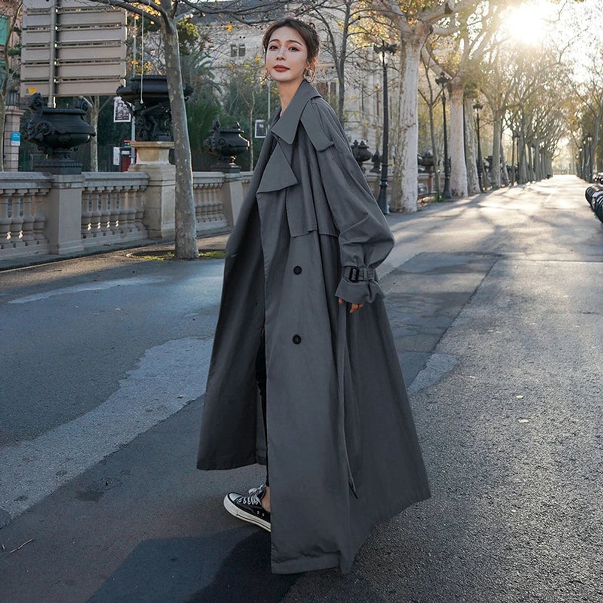 Women's full-length belted trench coat with wide lapels and buckle cuffs
