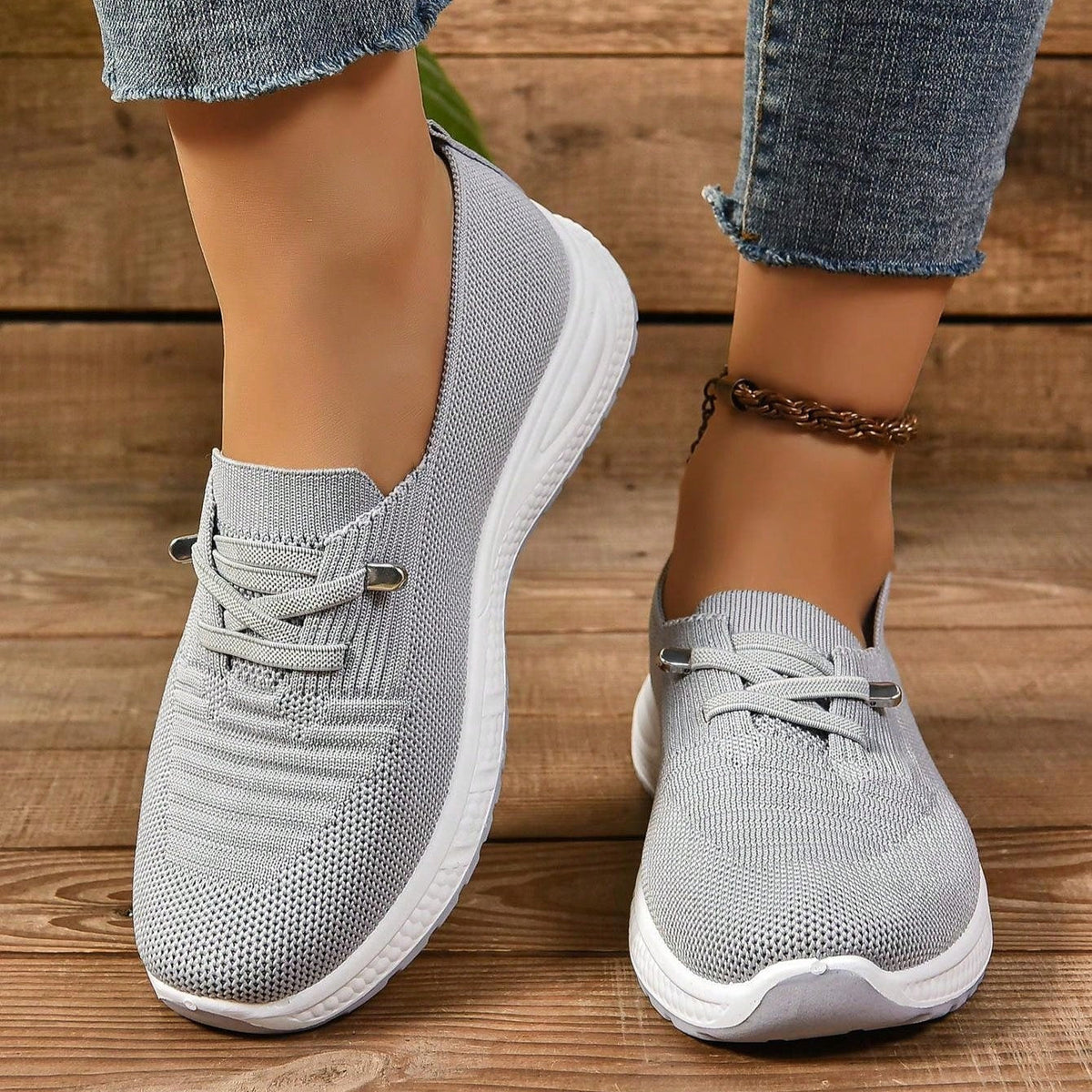 Grey women's slip-on sneakers with elastic lace detail and white soles
