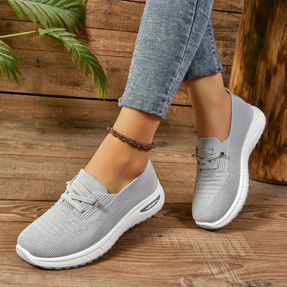 Grey women's slip-on sneakers with elastic lace detail and white soles
