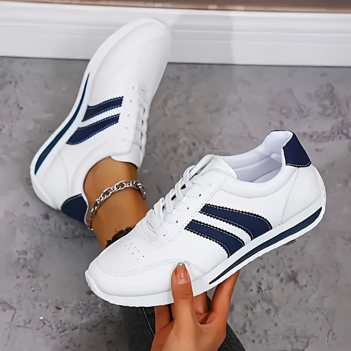 White lace-up sneakers with navy side stripes and flat soles