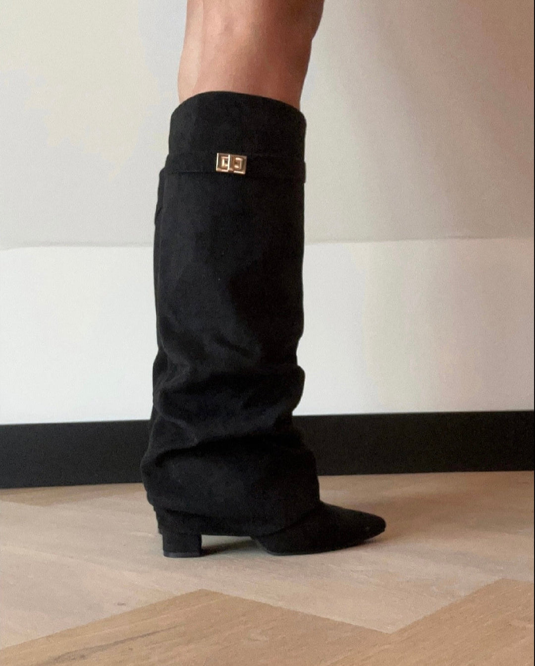 Black women's slouch knee-high boots with pointed toes and buckle details