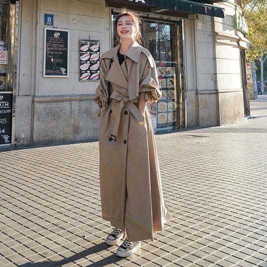 Women's full-length belted trench coat with wide lapels and buckle cuffs