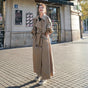 Women's full-length belted trench coat with wide lapels and buckle cuffs