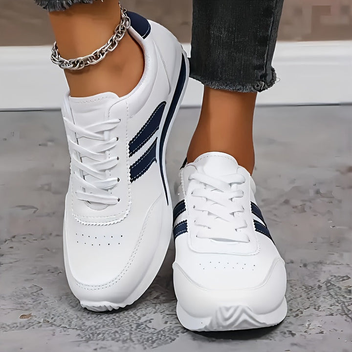 White lace-up sneakers with navy side stripes and flat soles