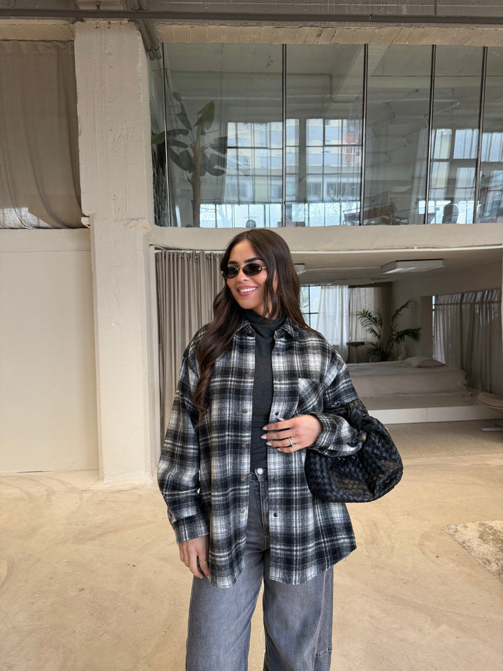 Women's black, gray and white plaid shirt layered over a dark turtleneck