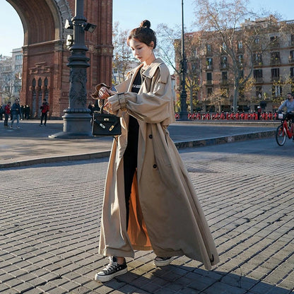 Women's full-length belted trench coat with wide lapels and buckle cuffs
