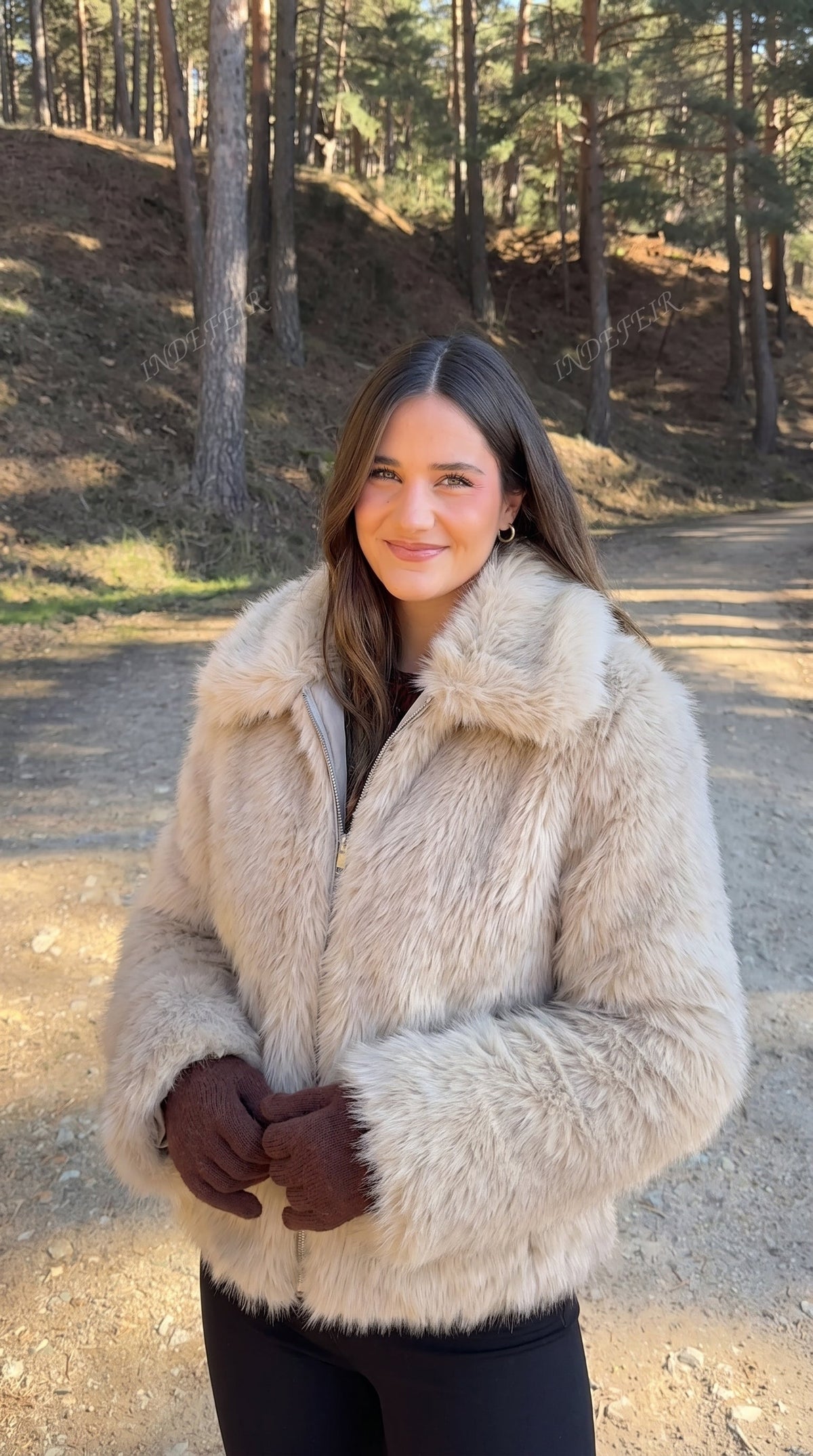 Woman wearing a beige faux fur bomber jacket with a wide collar and long sleeves