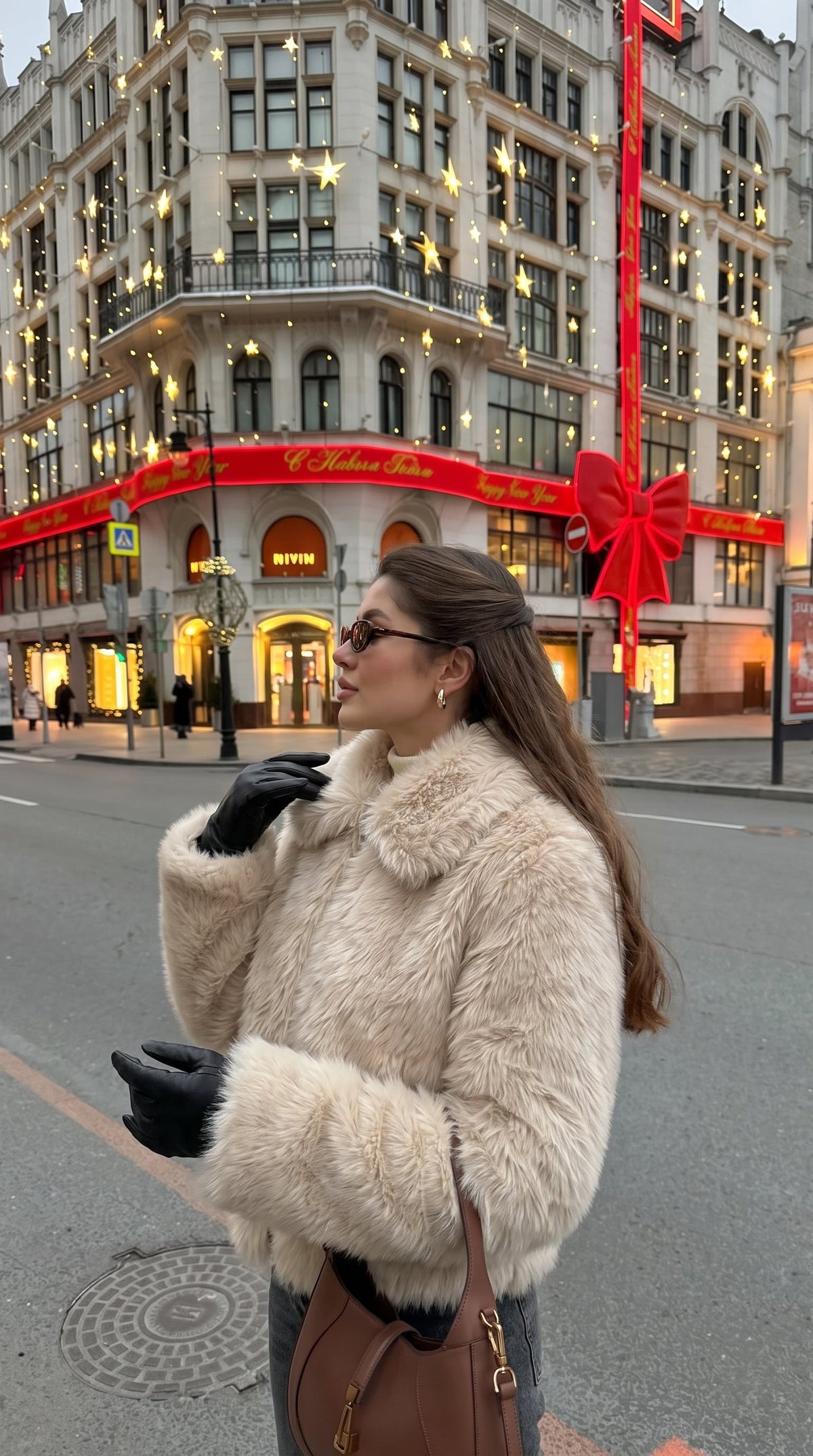 Woman wearing a beige faux fur bomber jacket with a wide collar and long sleeves