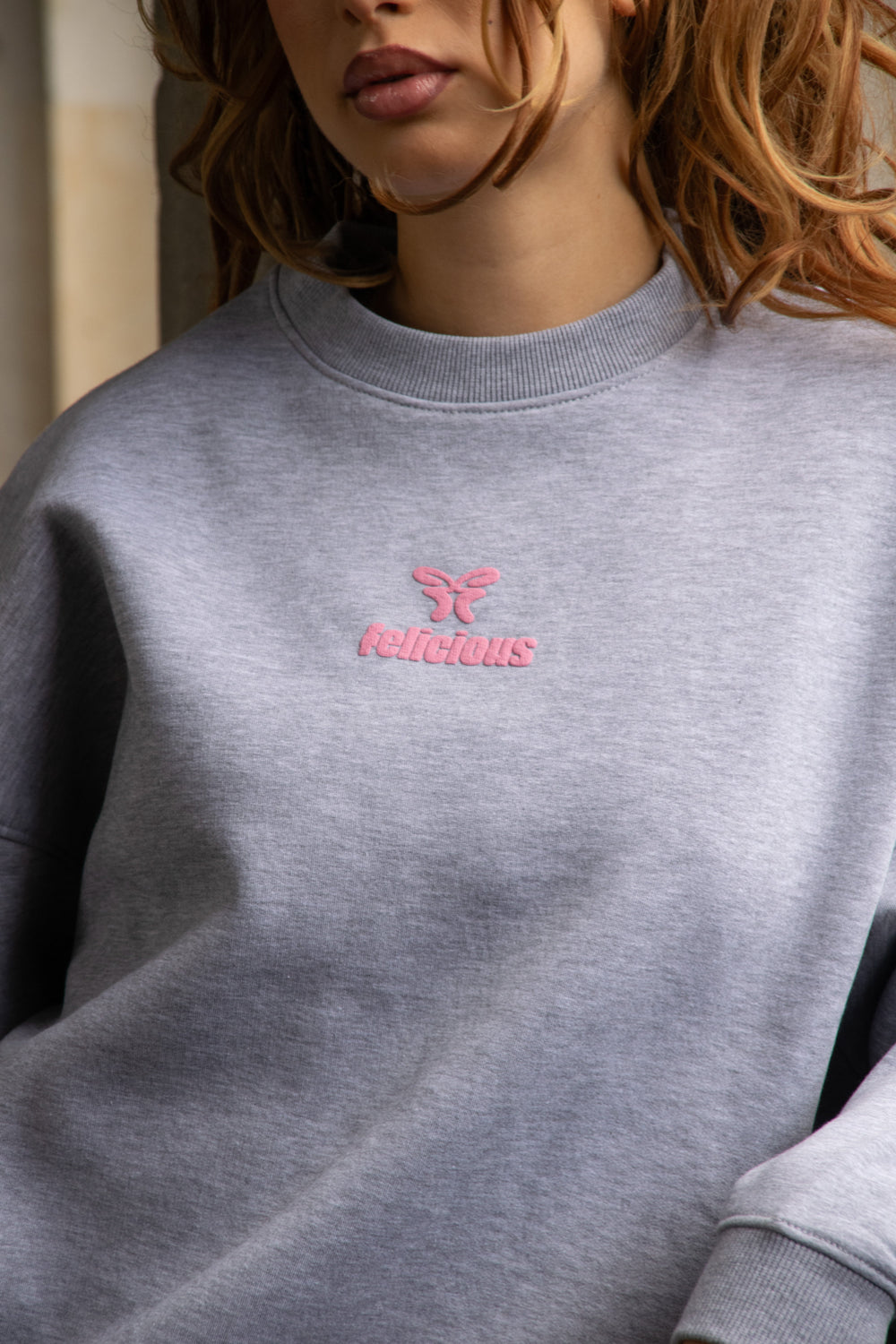 Women's gray crewneck sweatshirt with pink chest logo
