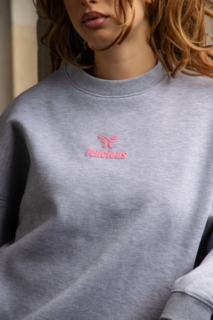 Women's gray crewneck sweatshirt with pink chest logo