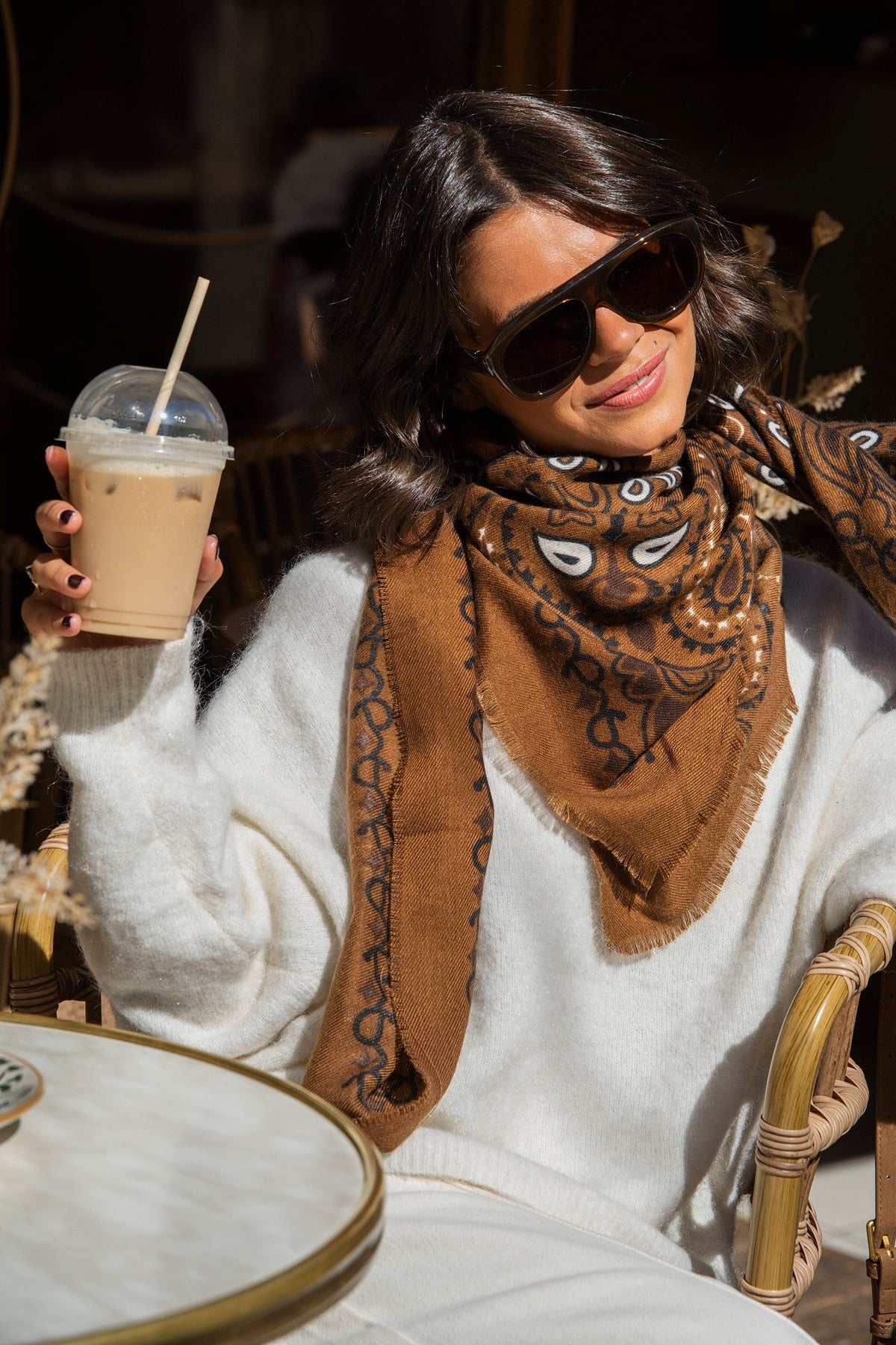 Brown paisley bandana scarf with fringed edges worn around the neck