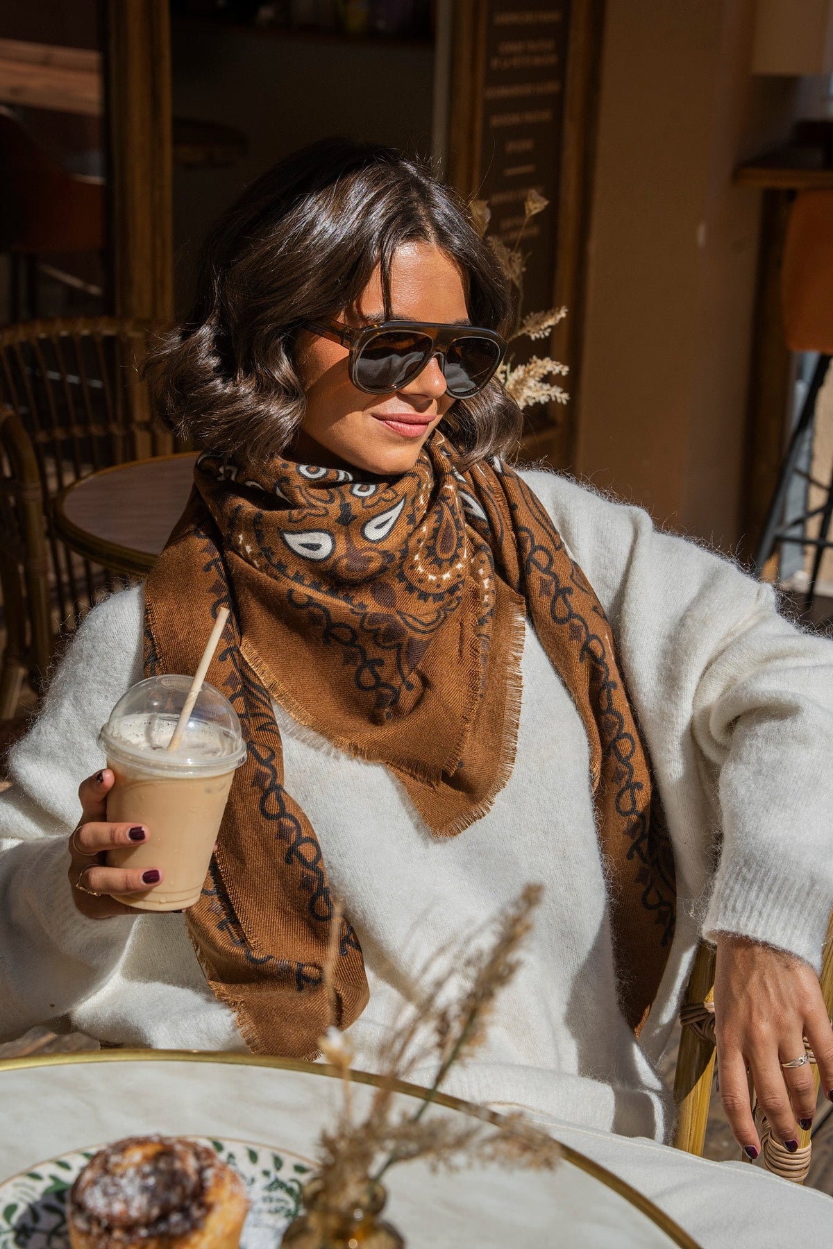 Brown paisley bandana scarf with fringed edges worn around the neck