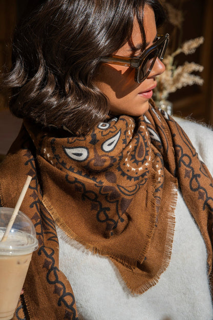 Brown paisley bandana scarf with fringed edges worn around the neck
