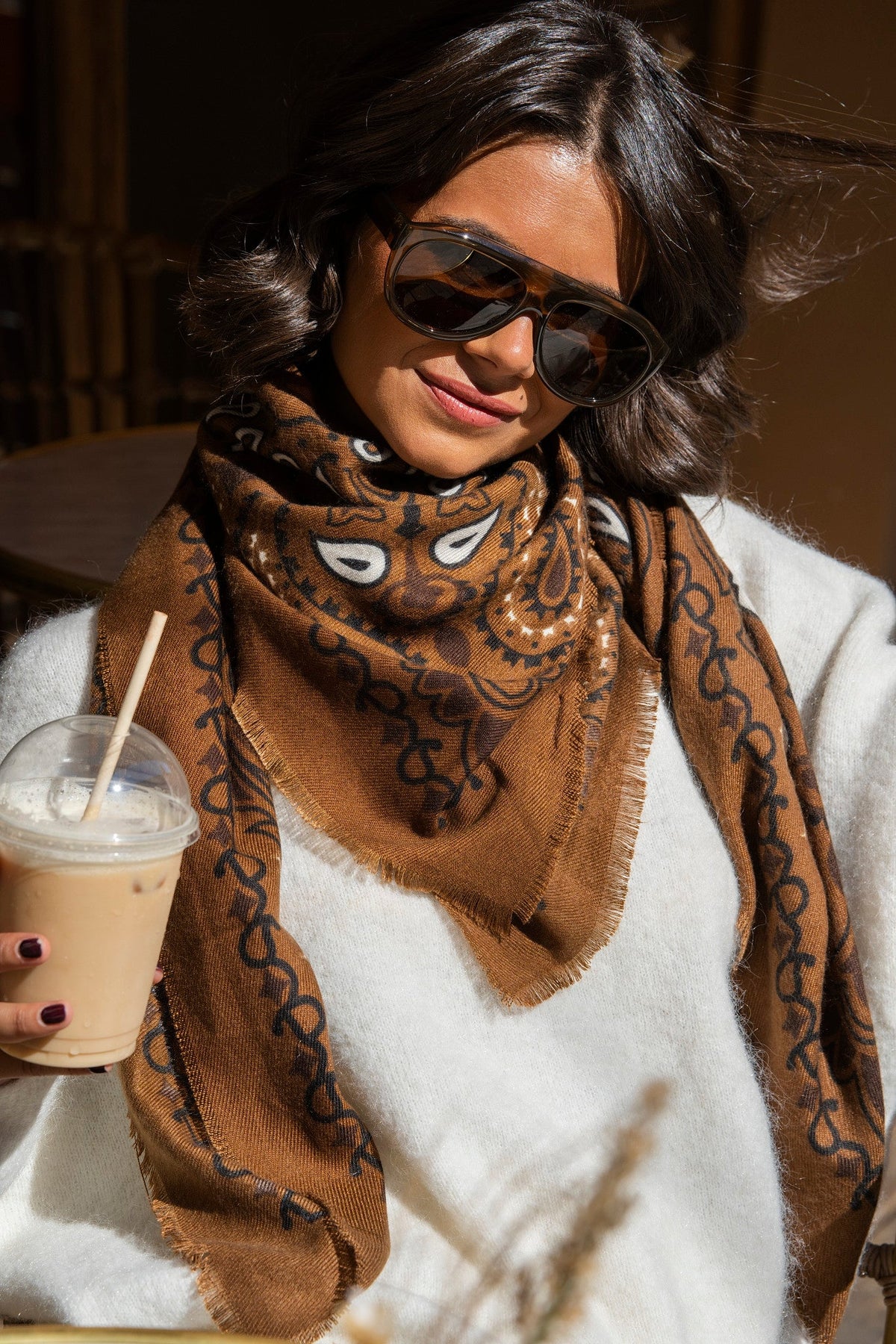 Brown paisley bandana scarf with fringed edges worn around the neck