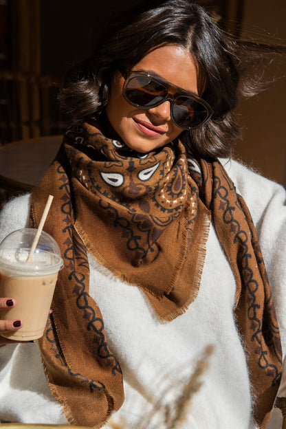 Brown paisley bandana scarf with fringed edges worn around the neck