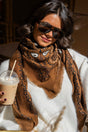 Brown paisley bandana scarf with fringed edges worn around the neck
