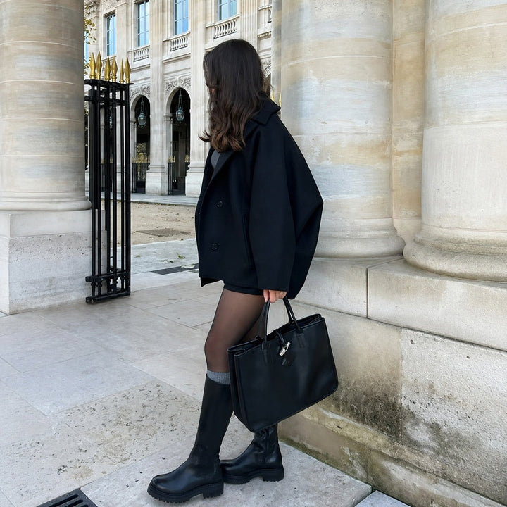 Woman wearing an oversized short coat with notched lapels, long sleeves and front pockets