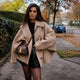 Woman wearing an oversized short coat with notched lapels, long sleeves and front pockets