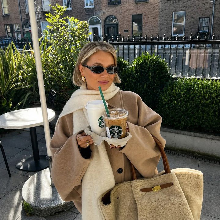 Woman wearing an oversized short coat with notched lapels, long sleeves and front pockets