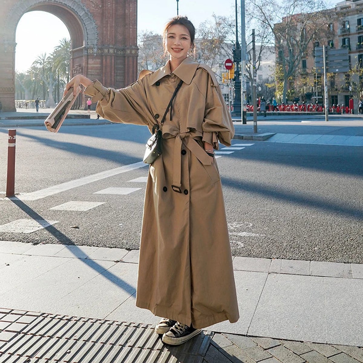 Women's full-length belted trench coat with wide lapels and buckle cuffs