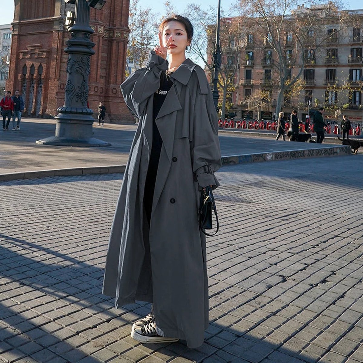 Women's full-length belted trench coat with wide lapels and buckle cuffs