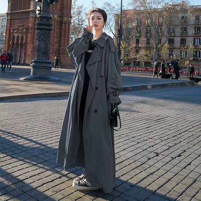Women's full-length belted trench coat with wide lapels and buckle cuffs