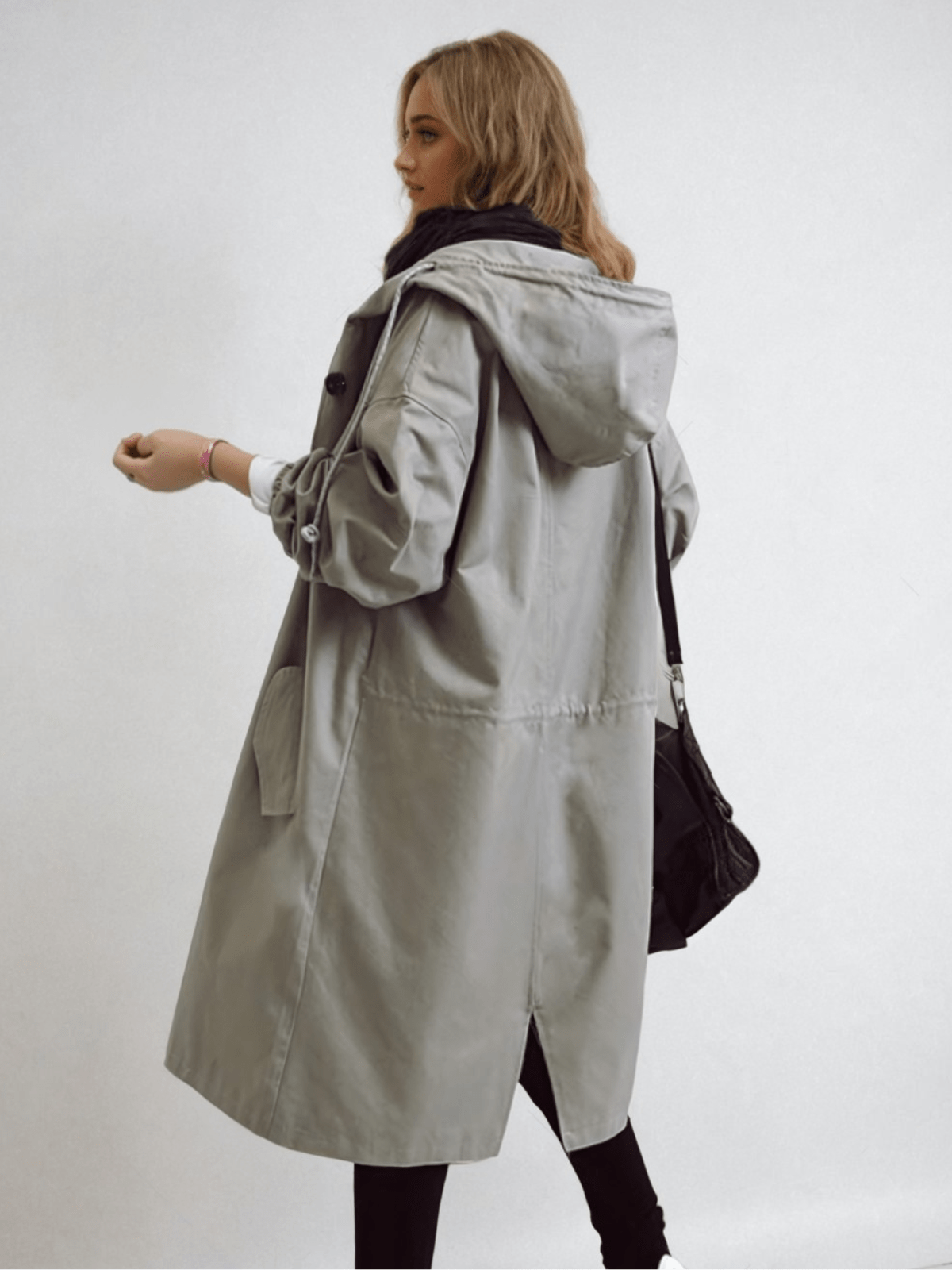 Woman wearing a longline hooded button-front trench coat with patch pockets