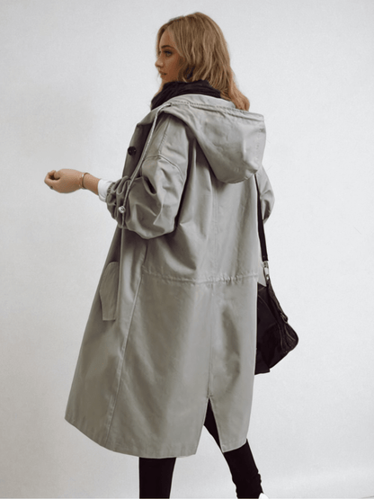 Woman wearing a longline hooded button-front trench coat with patch pockets