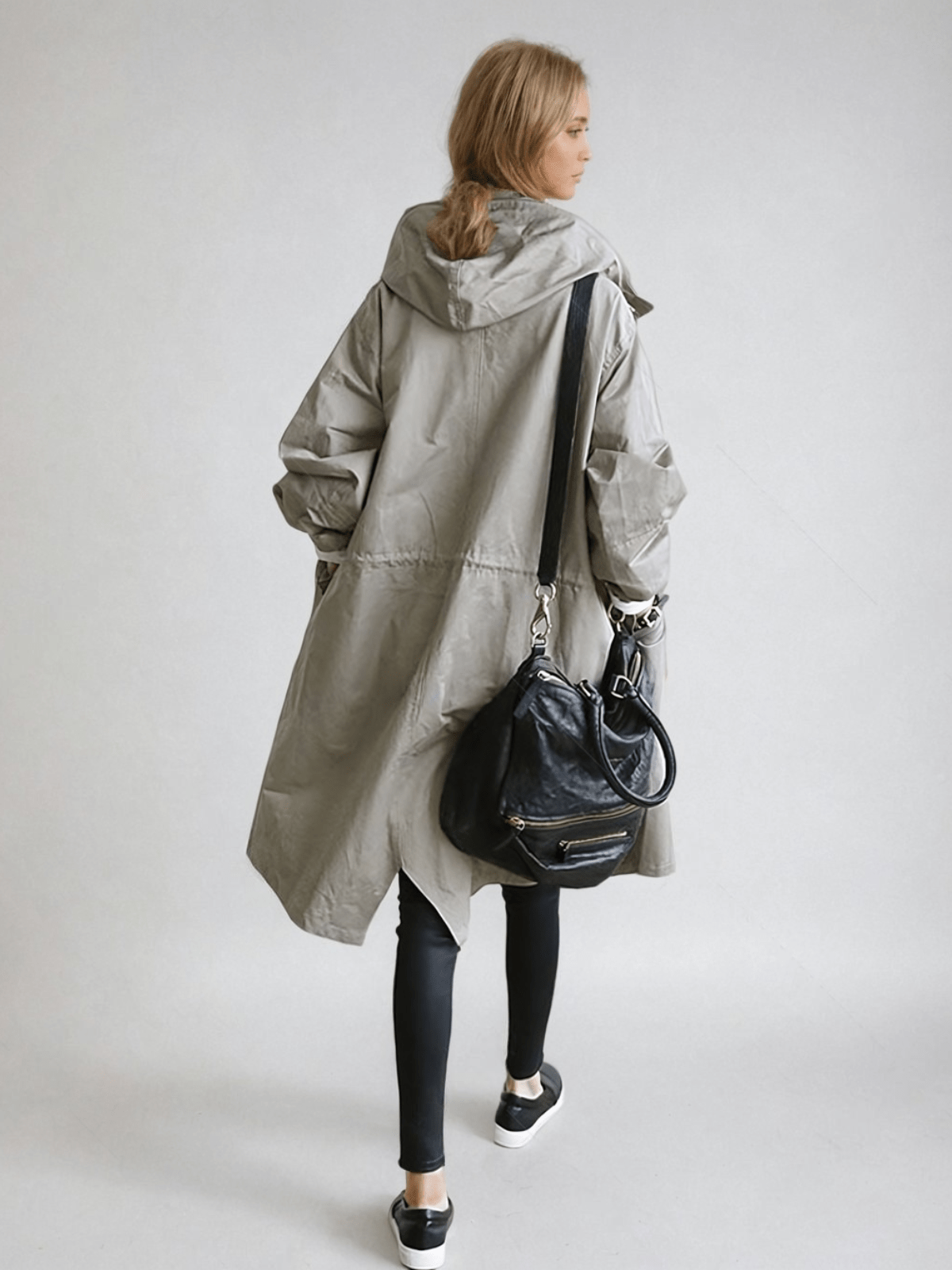 Woman wearing a longline hooded button-front trench coat with patch pockets