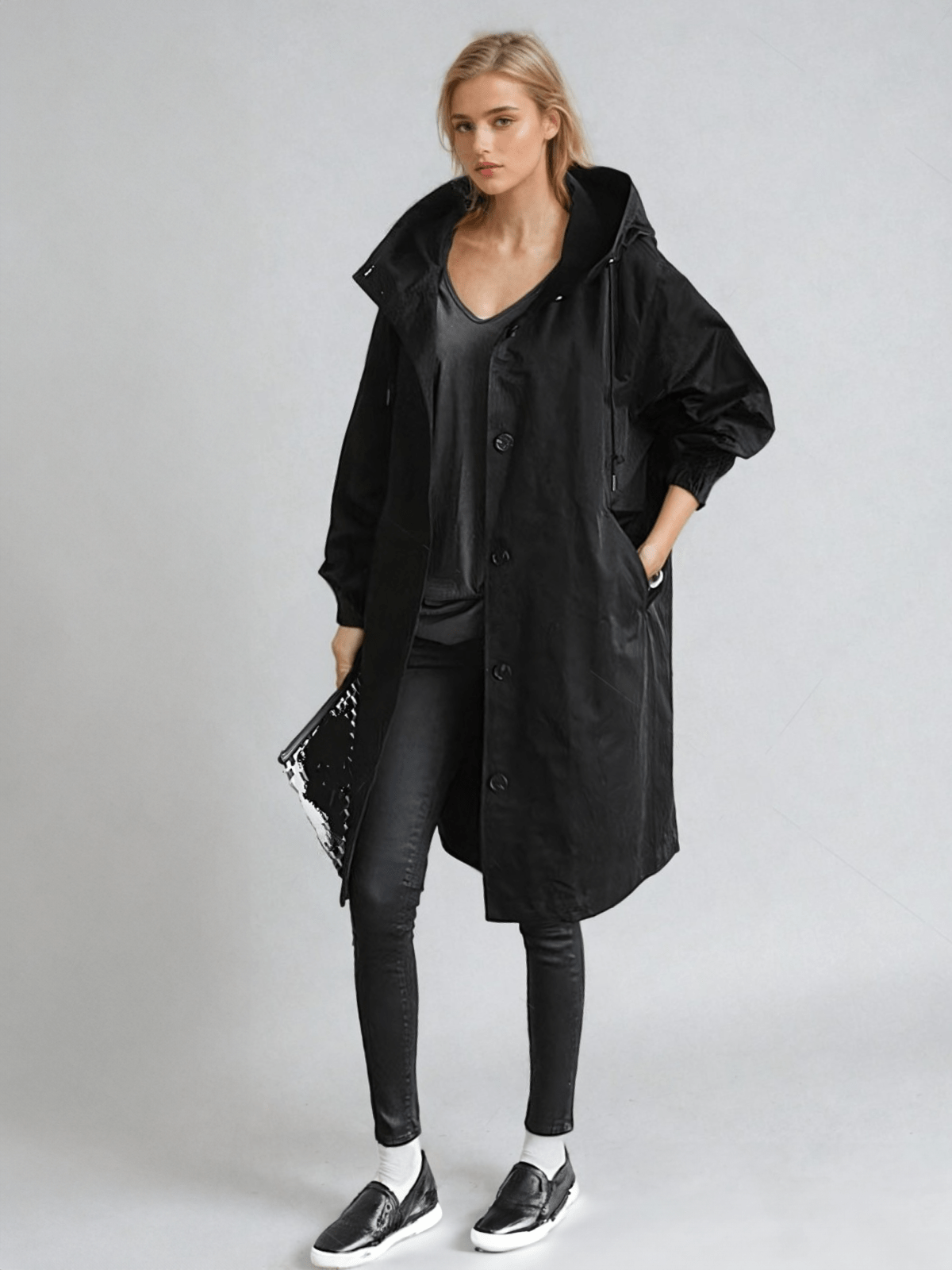 Woman wearing a longline hooded button-front trench coat with patch pockets