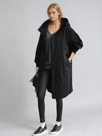 Woman wearing a longline hooded button-front trench coat with patch pockets