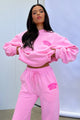 Women's pink cropped hoodie with long sleeves, front pouch pocket and chest text detail
