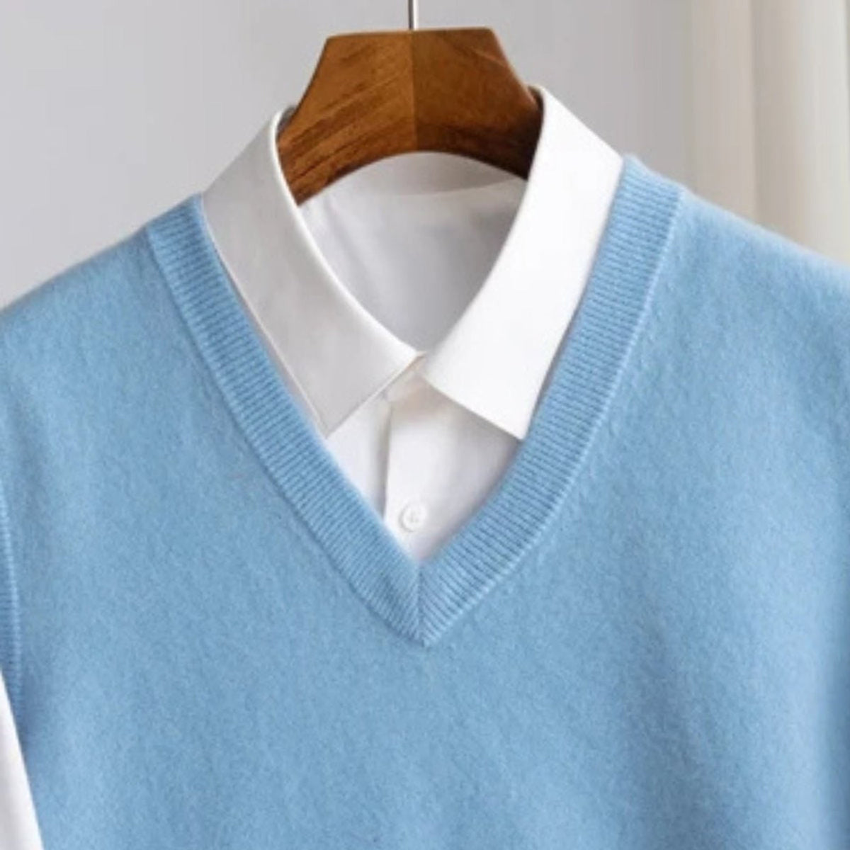 Women's sleeveless V-neck knit sweater vest layered over a white collared shirt
